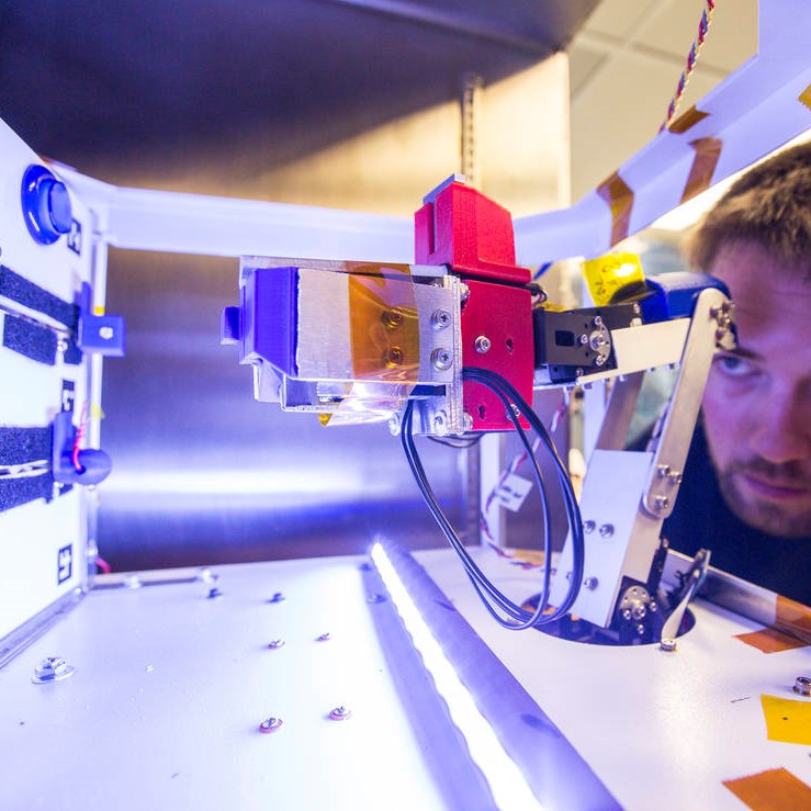 Spencer Lee, of Durham Techinical Community College's Unacceptable Risks, peers at the RAM3 autonomous robotic arm following thermal vacuum chamber testing at NASA's Langley Research Center in Hampton, Virginia.